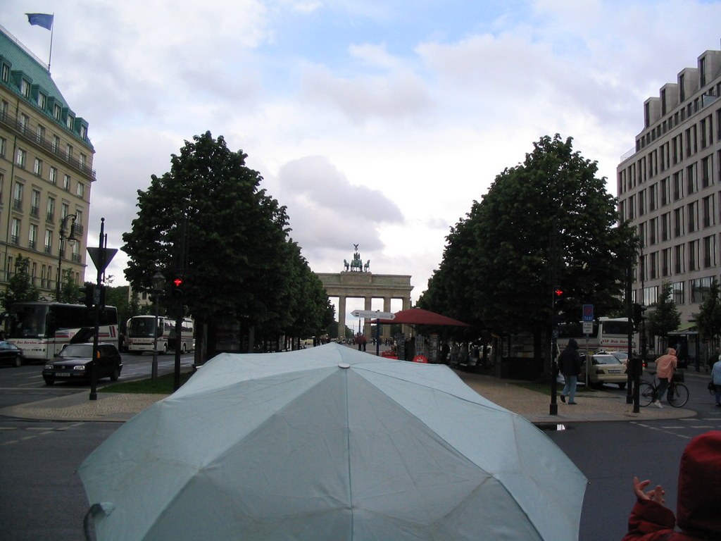 Blick über einen aufgespannten Regenschirm die Straße entlang zum Brandenburger Tor