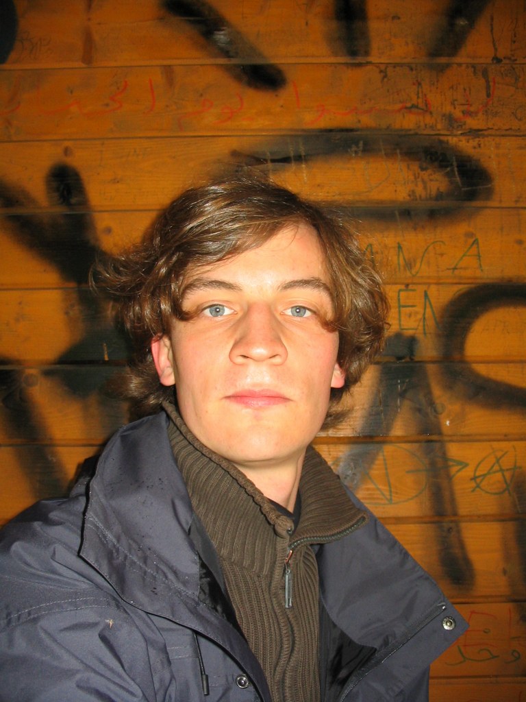 Selbstporträt von Tim Meyer unterwegs, vor einer Wand mit Graffiti