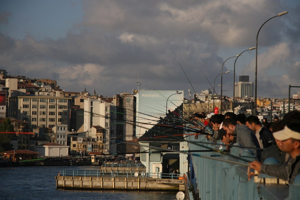 Angler dicht an dicht am Geländer der Galata-Brücke, dahinter Beyoğlu im Abendlicht
