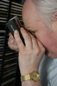 Josef Arens hält eine CD-Hülle dicht vors Auge und liest den Titel mit einer Lupe